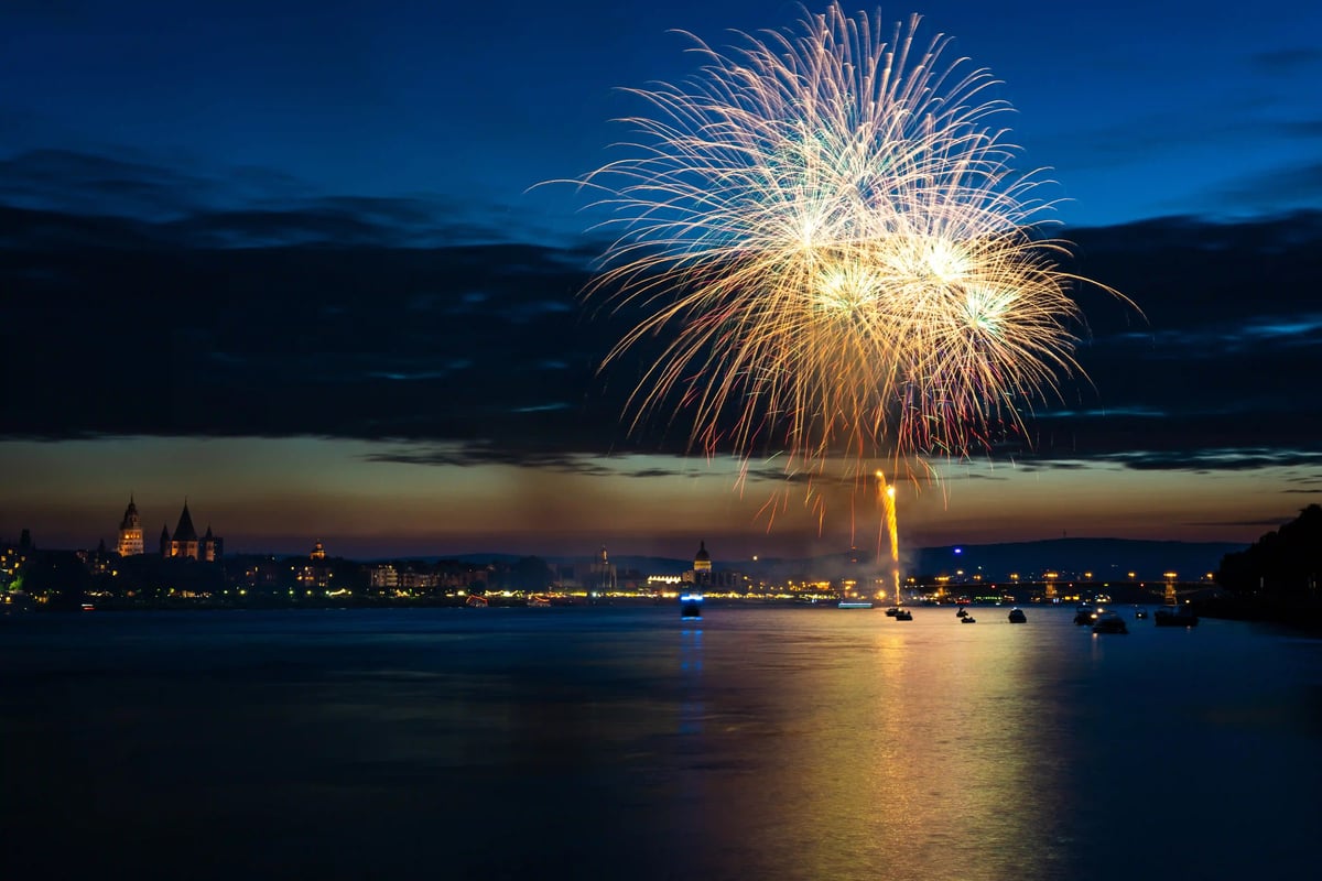 Grosses Feuerwerk erleuchtet den Nachthimmel über dem Rhein und einer beleuchteten Stadt