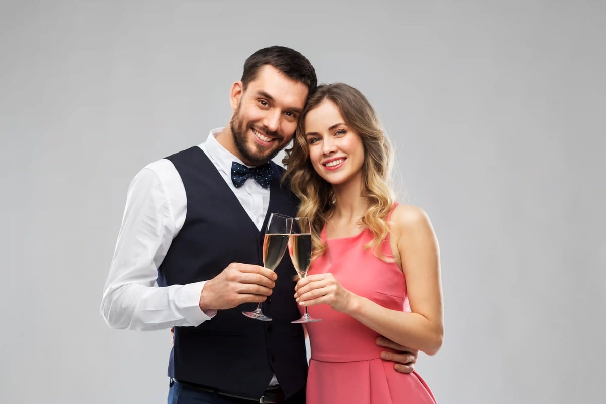 Elegantes Paar stösst lächelnd mit Sektgläsern an und feiert festlichen Silvesterabend