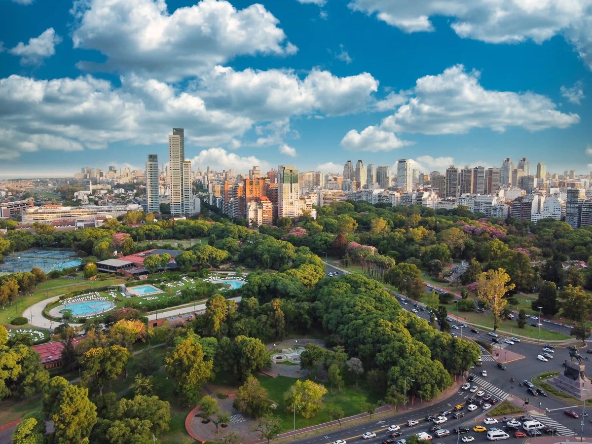 Blick auf eine große grüne Parkanlage in Buenos Aires mit Hochhäusern im Hintergrund unter blauem Himmel