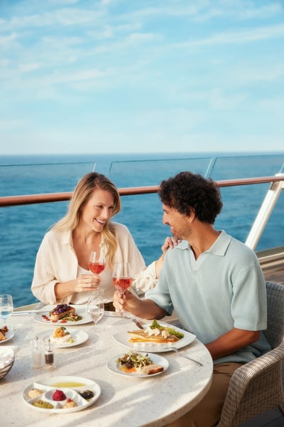 Paar sitzt beim Abendessen an Bord eines Kreuzfahrtschiffes mit Blick auf das Meer