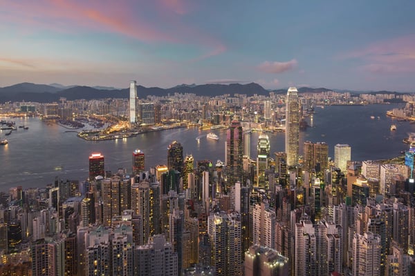 Dichte Hochhäuser von Hongkong bei Abenddämmerung mit Hafen und Lichtern