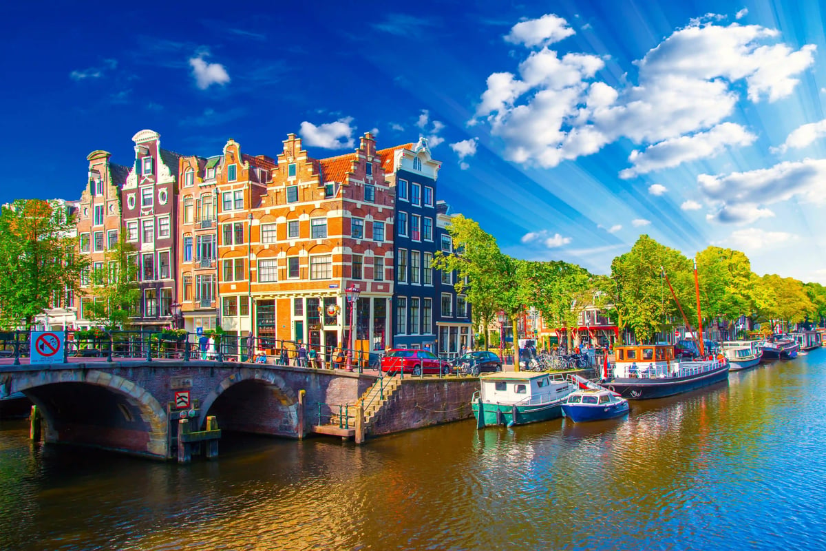 Maisons traditionnelles des canaux dAmsterdam se reflétant dans leau calme sous un ciel bleu