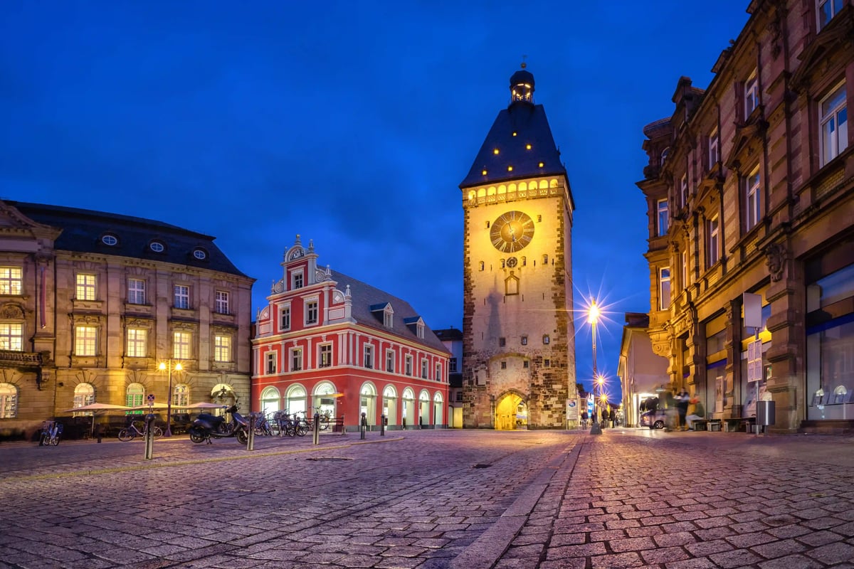 La porte Altpörtel illuminée à Spire la nuit, entourée de bâtiments historiques et de pavés