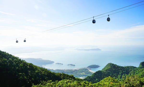 Seilbahn über grünen Bergen mit Blick auf Inseln und Meer in tropischer Landschaft