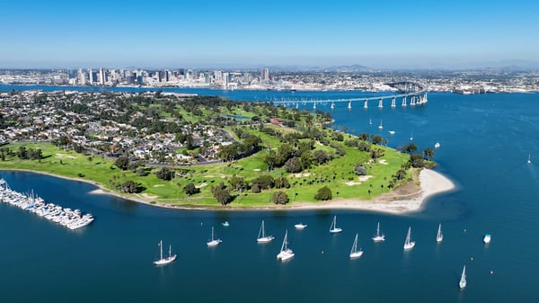 Luftaufnahme von Küste mit Park, Booten im Wasser und Stadt im Hintergrund