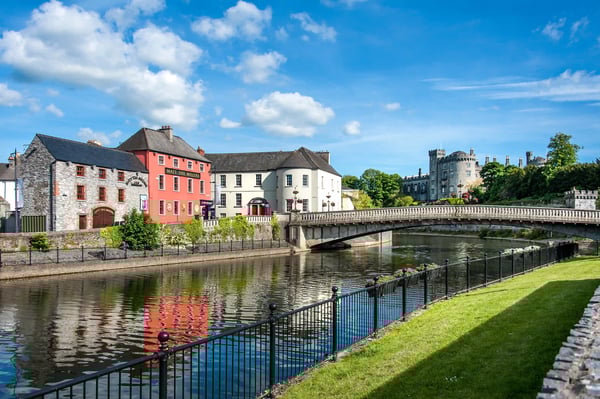 Vue de Kilkenny avec riviere, pont en pierre, maisons colorees et chateau en arriere plan