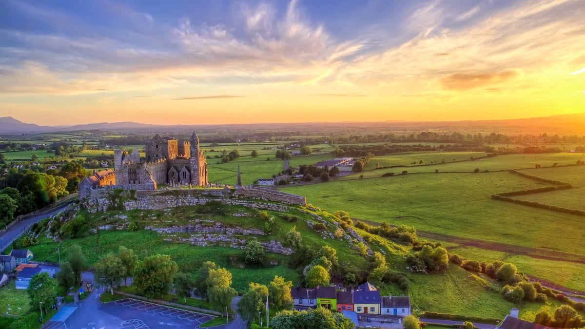 Vue aerienne du Rock of Cashel au coucher du soleil, entoure de collines verdoyantes et de paysages ruraux irlandais