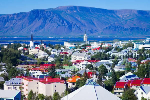Vue panoramique de Reykjavik avec maisons colorées, église emblématique et montagnes au loin.