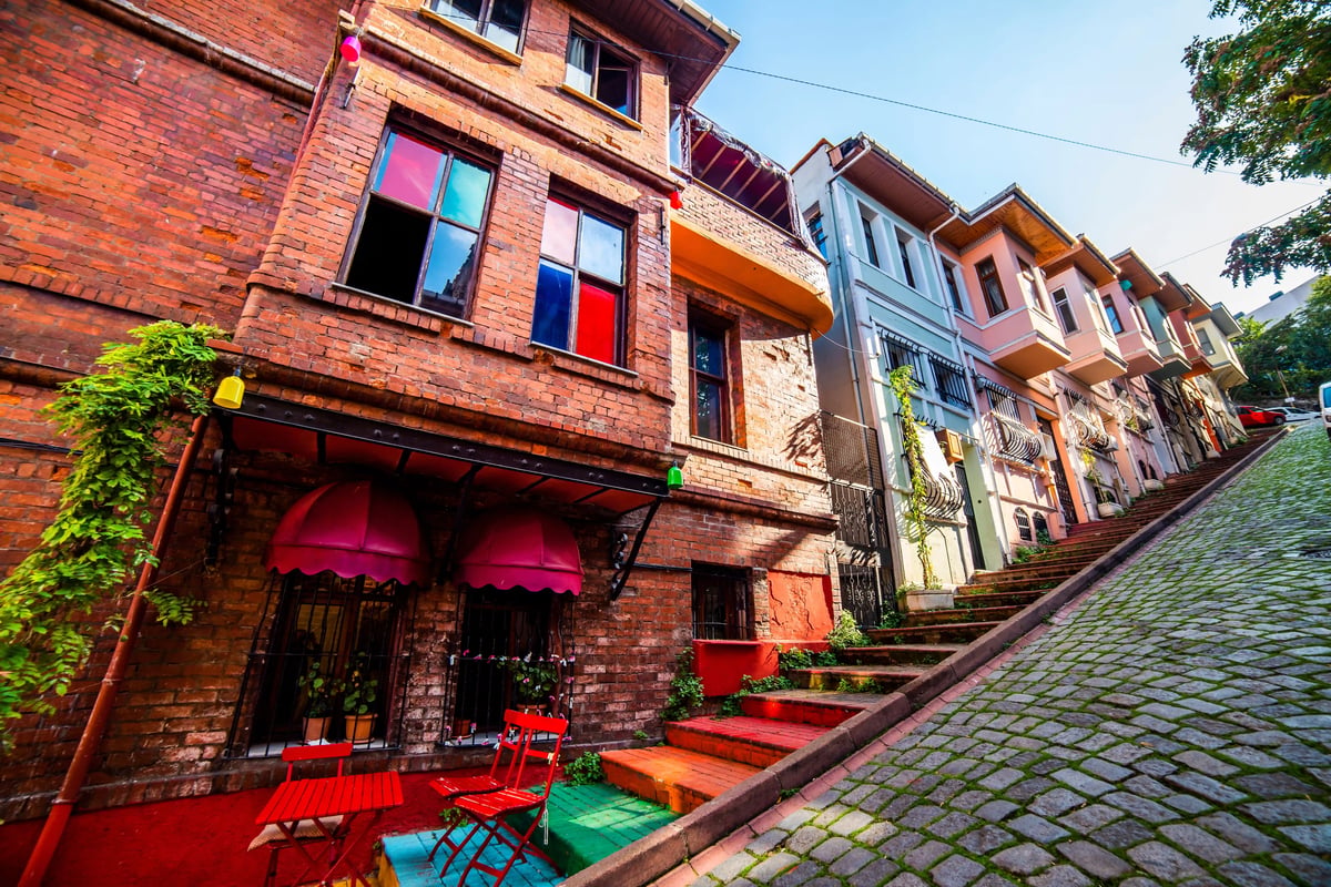 Rue en pente du quartier Balat avec maisons colorées, escaliers et mobilier urbain.