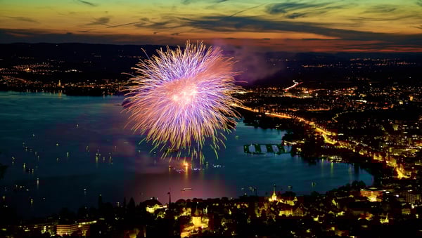 Feu d’artifice nocturne au-dessus d’un lac suisse illuminant la ville et les rives.