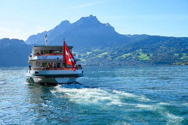 Bateau de passagers naviguant sur le lac des Quatre-Cantons avec montagnes en arrière-plan.
