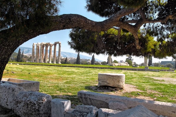 Ruines du temple de Zeus à Olympie, colonnes antiques sur une prairie verte.