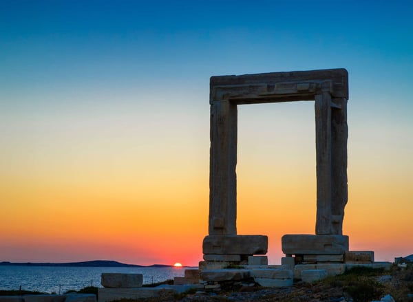 Porte monumentale en marbre de Portara au coucher du soleil, face à la mer.