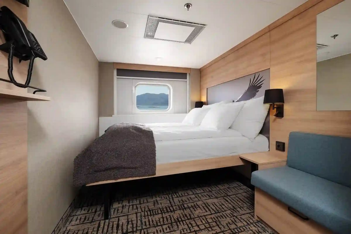 Cabine extérieure moderne à bord d’un navire Hurtigruten avec lit double et vue sur la mer.
