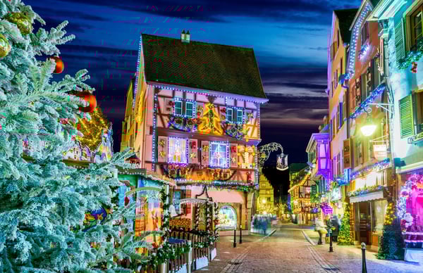 Rue pittoresque de Colmar en période de Noël avec façades traditionnelles, lumières festives et visiteurs se promenant