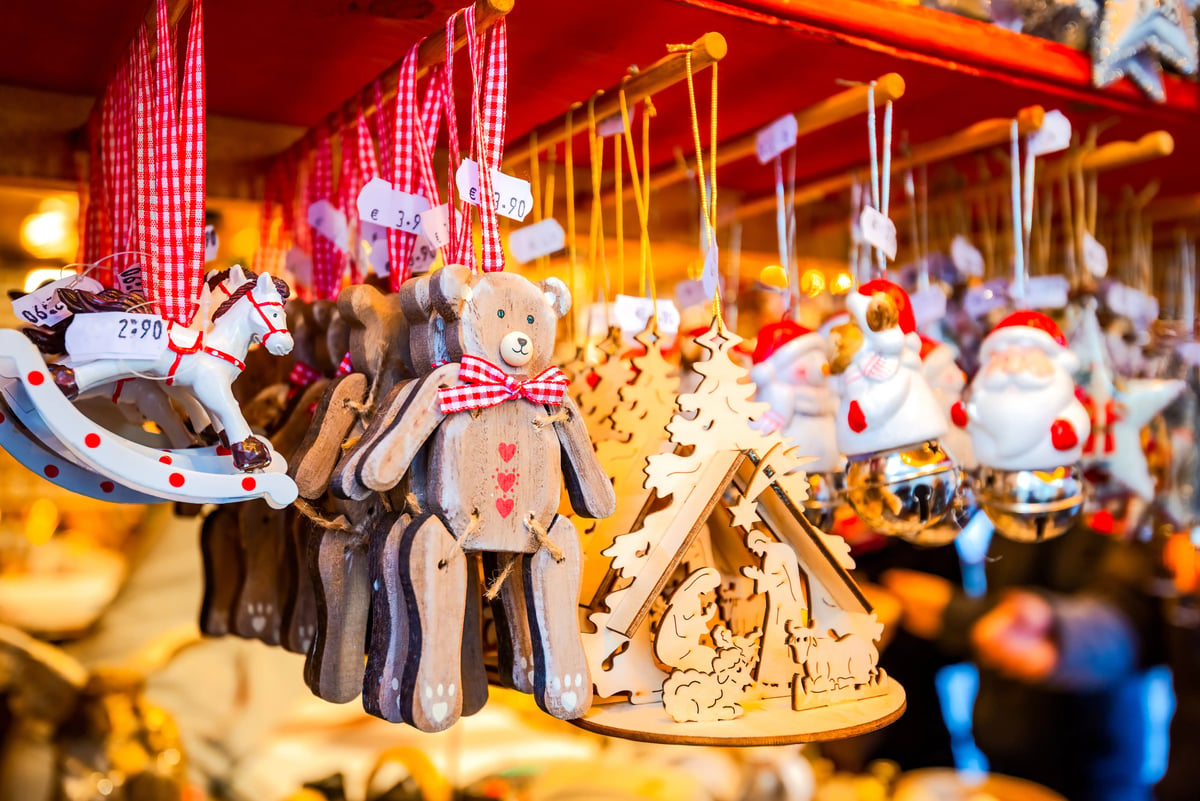 Gros plan sur des décorations de Noël artisanales en bois suspendues sur un stand de marché