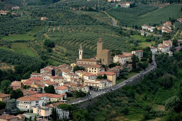 Petit village avec maisons et tour entouré de collines verdoyantes