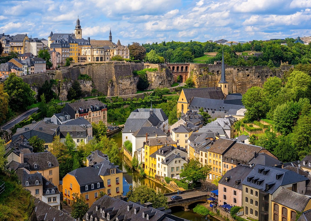 Blick auf die Altstadt von Luxemburg mit Häusern, Kirchen und Festungsmauern über einem grünen Tal.