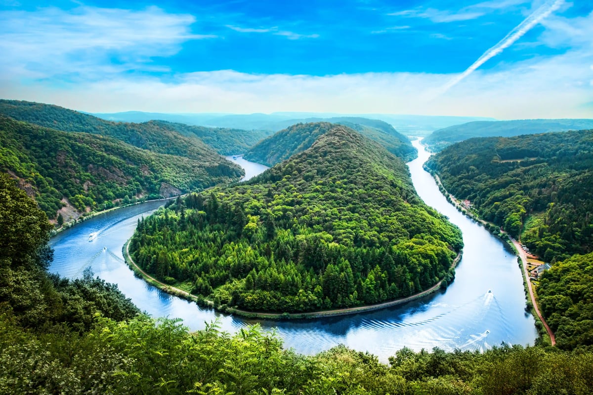 Luftbild der Saarschleife, der Fluss windet sich in einer engen Kurve durch dicht bewaldete Hügel.