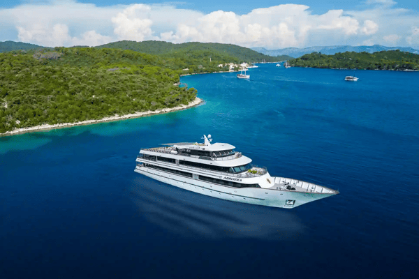Navire de croisière MS Adriatica naviguant sur une mer bleue près de la côte boisée