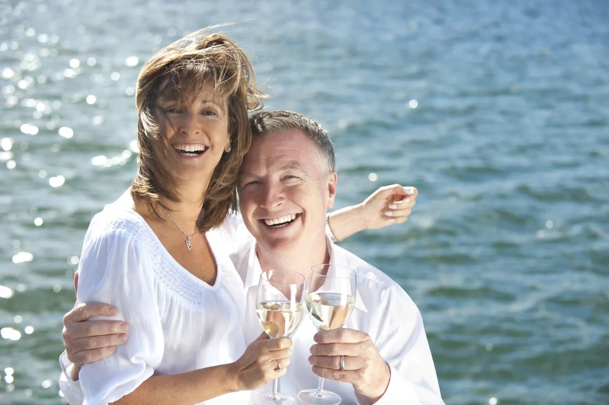 Couple joyeux trinquant avec des verres de vin au bord de la mer