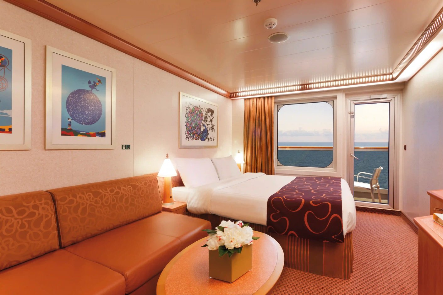 Balkonkabine auf Kreuzfahrtschiff mit Doppelbett, Sofa und Meerblick durch Glastür