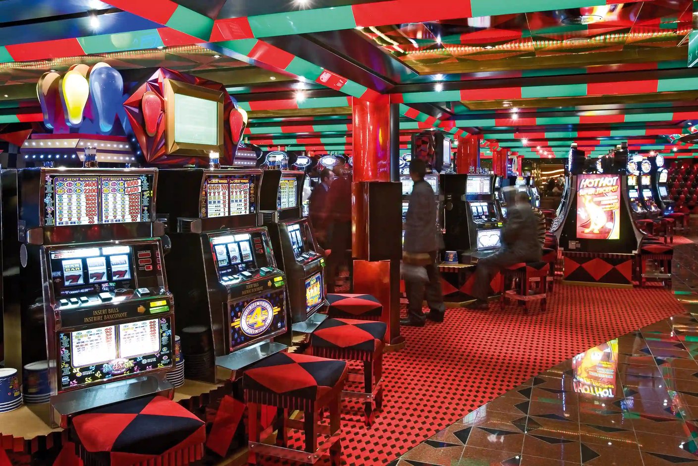 Casino mit Spielautomaten, Spieltischen und farbiger Deckenbeleuchtung