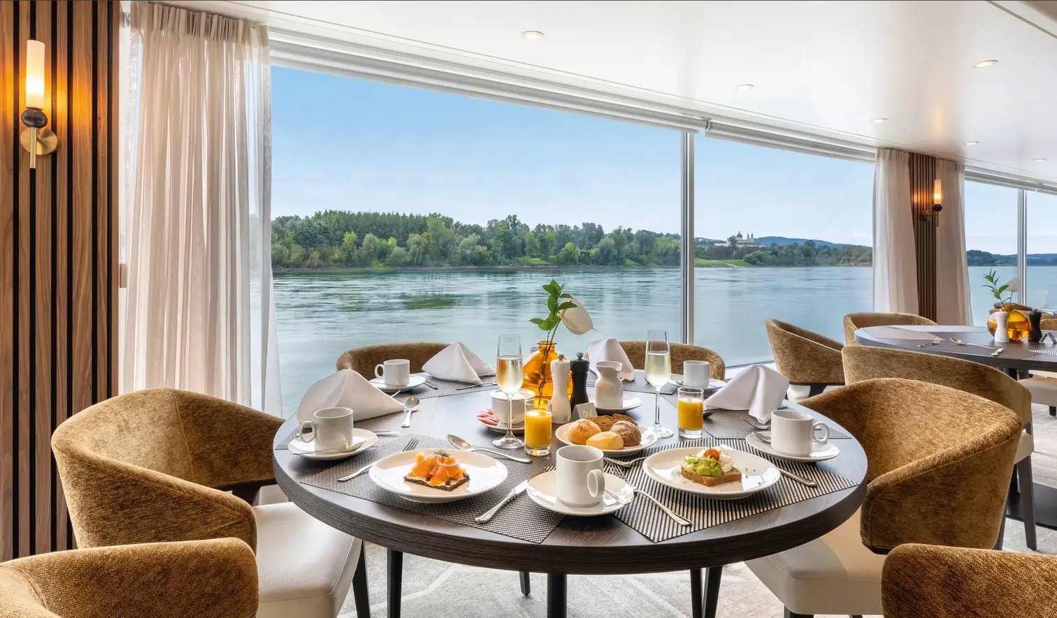Restaurant an Bord eines Flusskreuzfahrtschiffes mit gedecktem Frühstückstisch und Flussblick
