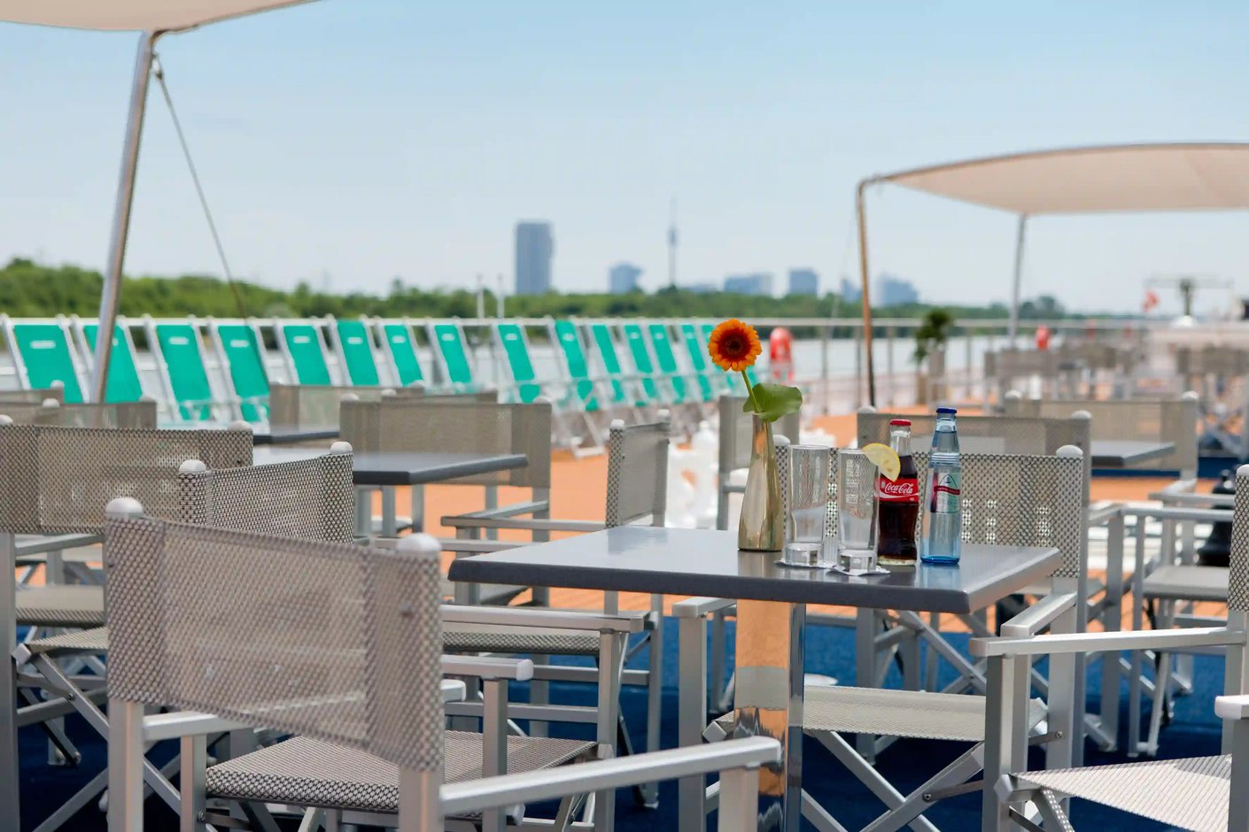 Sonnendeck mit Tischen, Stühlen und Blick auf den Fluss