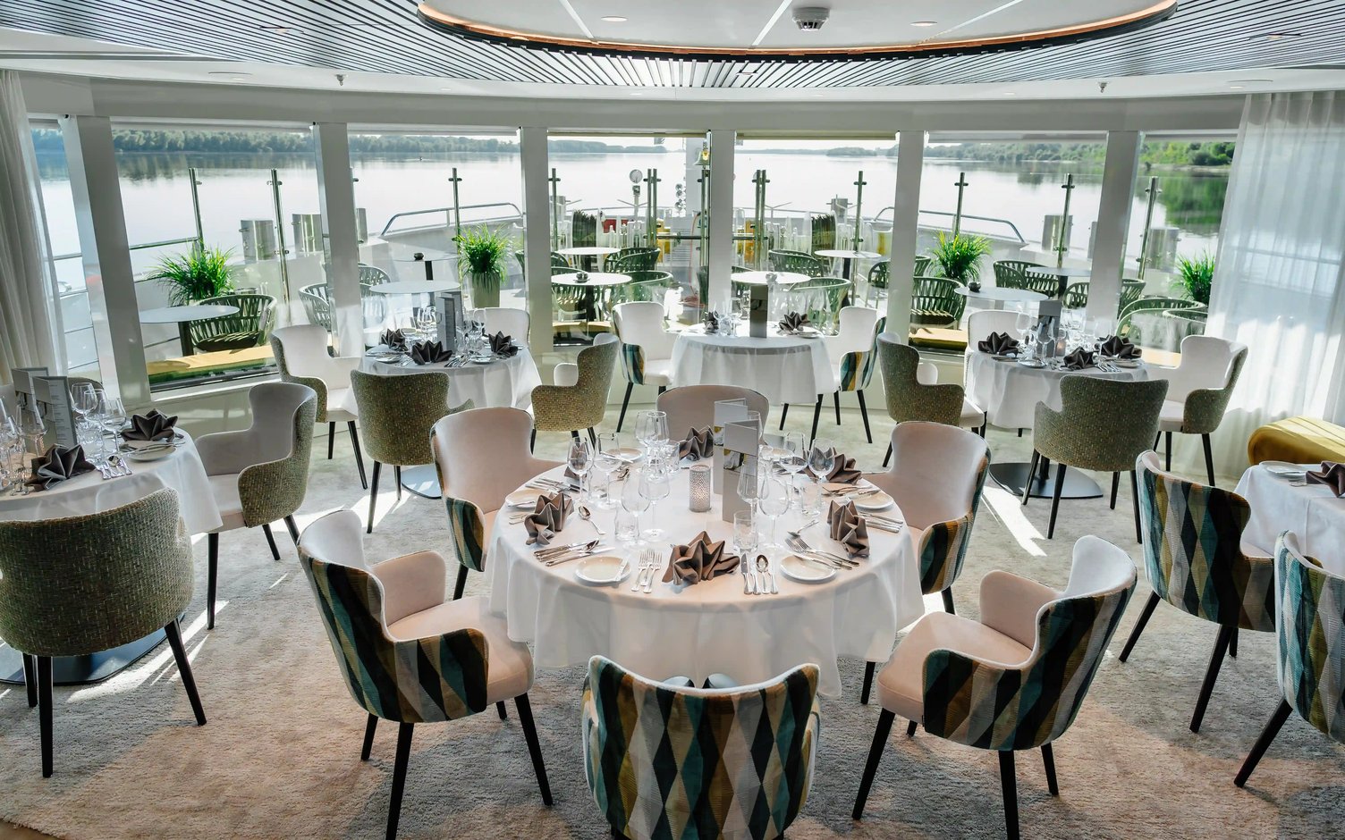 Restaurant eines Flusskreuzfahrtschiffs mit Rundtischen und Flussblick