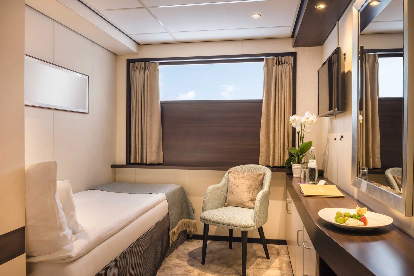 Einzelkabine mit Einzelbett, Fenster, Schreibtisch, Stuhl, Spiegel und heller Einrichtung