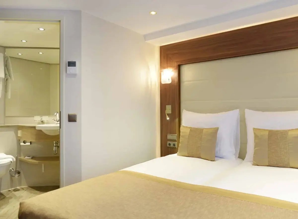 Luxuriöse Suite mit Doppelbett, Sitzecke und einem französischen Balkon mit Blick auf die Landschaft.