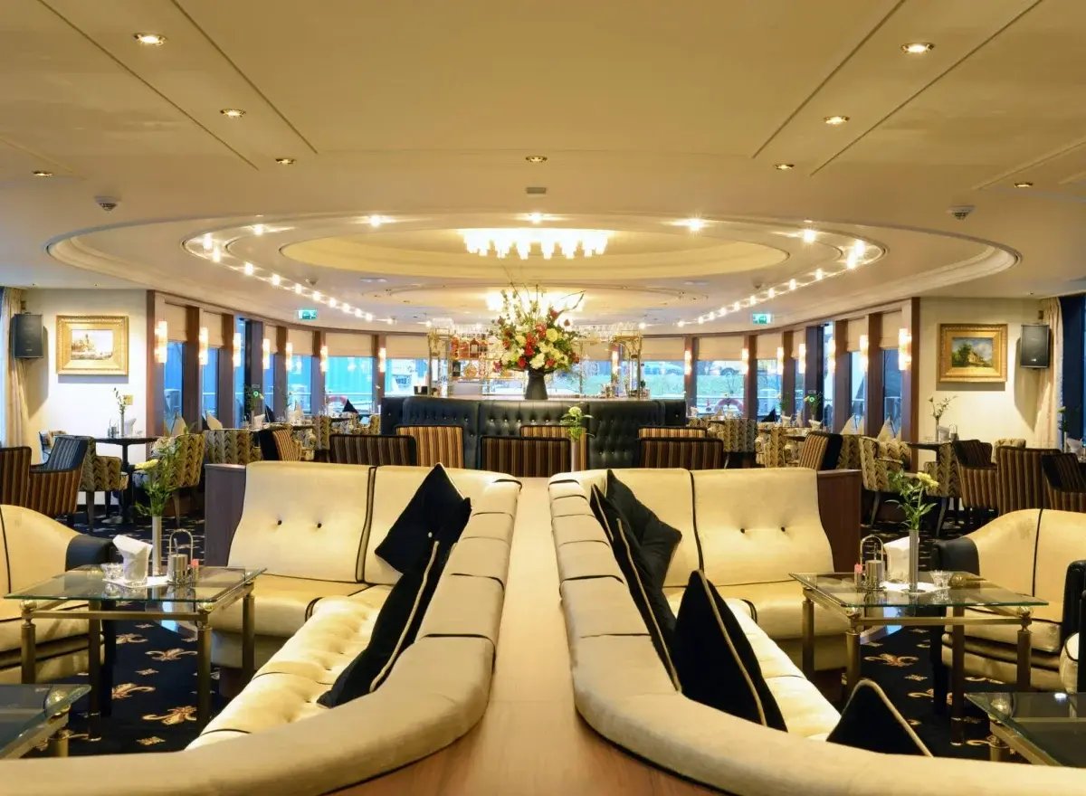 Gemütliche Lounge mit komfortablen Sesseln, Teppichboden und Rundumblick auf das Wasser.