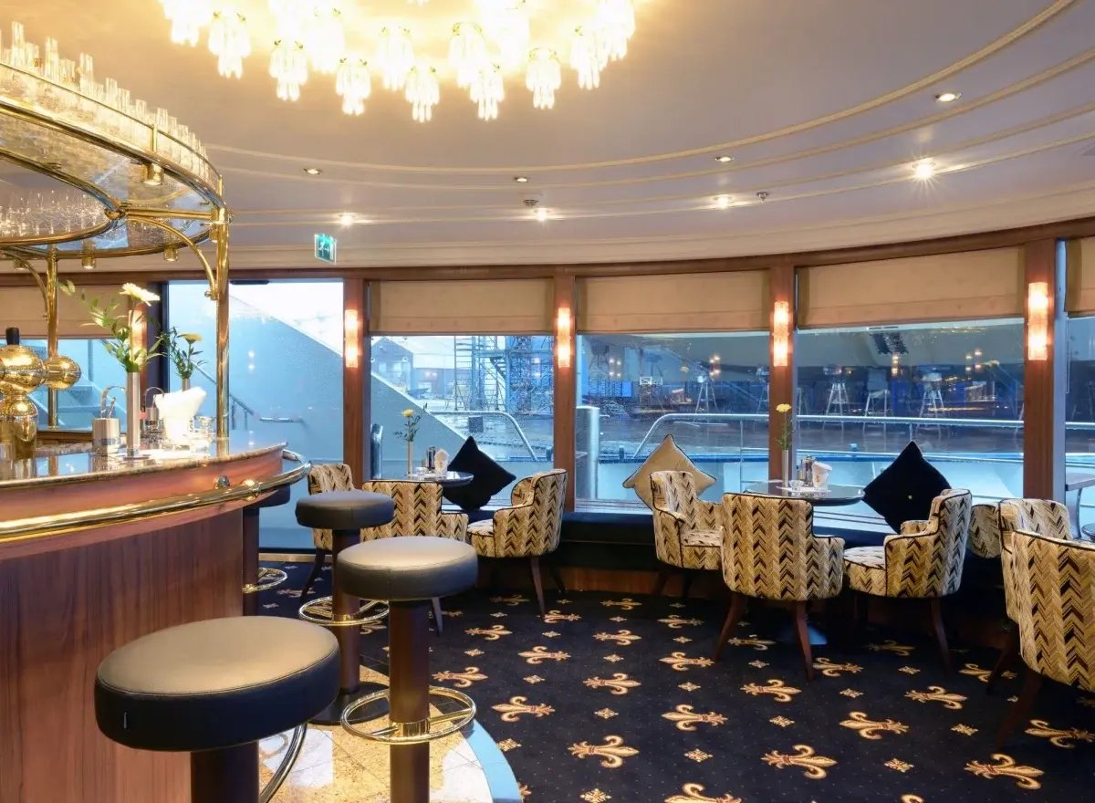 Stilvoll gestalteter Barbereich mit Barhockern und einer Auswahl an Getränken in elegantem Ambiente.