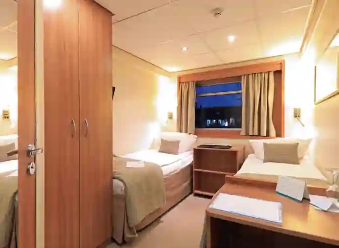 Gemütliche Kabine mit zwei Einzelbetten, Fenster, Schreibtisch und Stauraum an Bord.