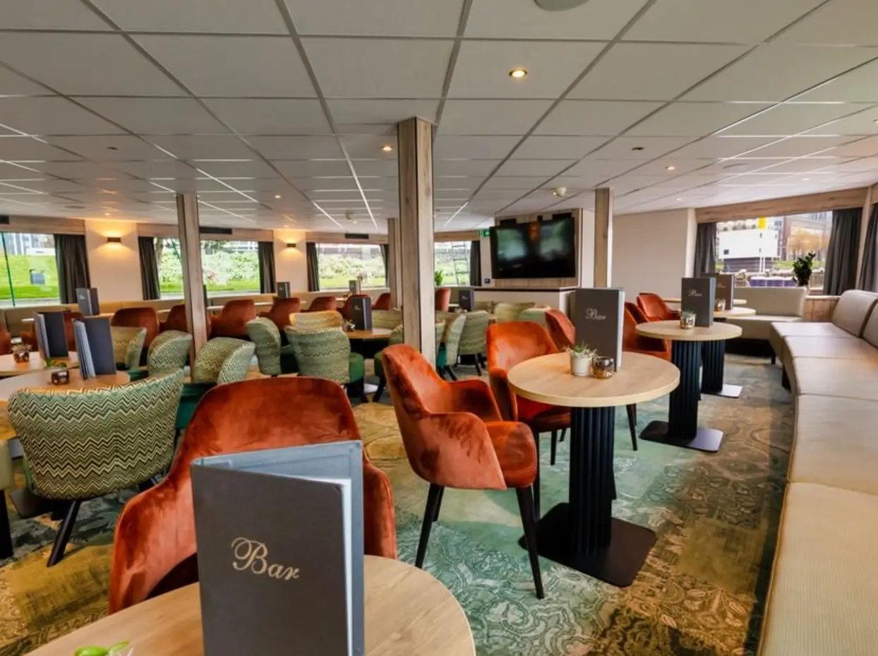 Panorama Bar mit kleinen Rundtischen, gepolsterten Sesseln, Bar Menükarten und Blick nach draussen