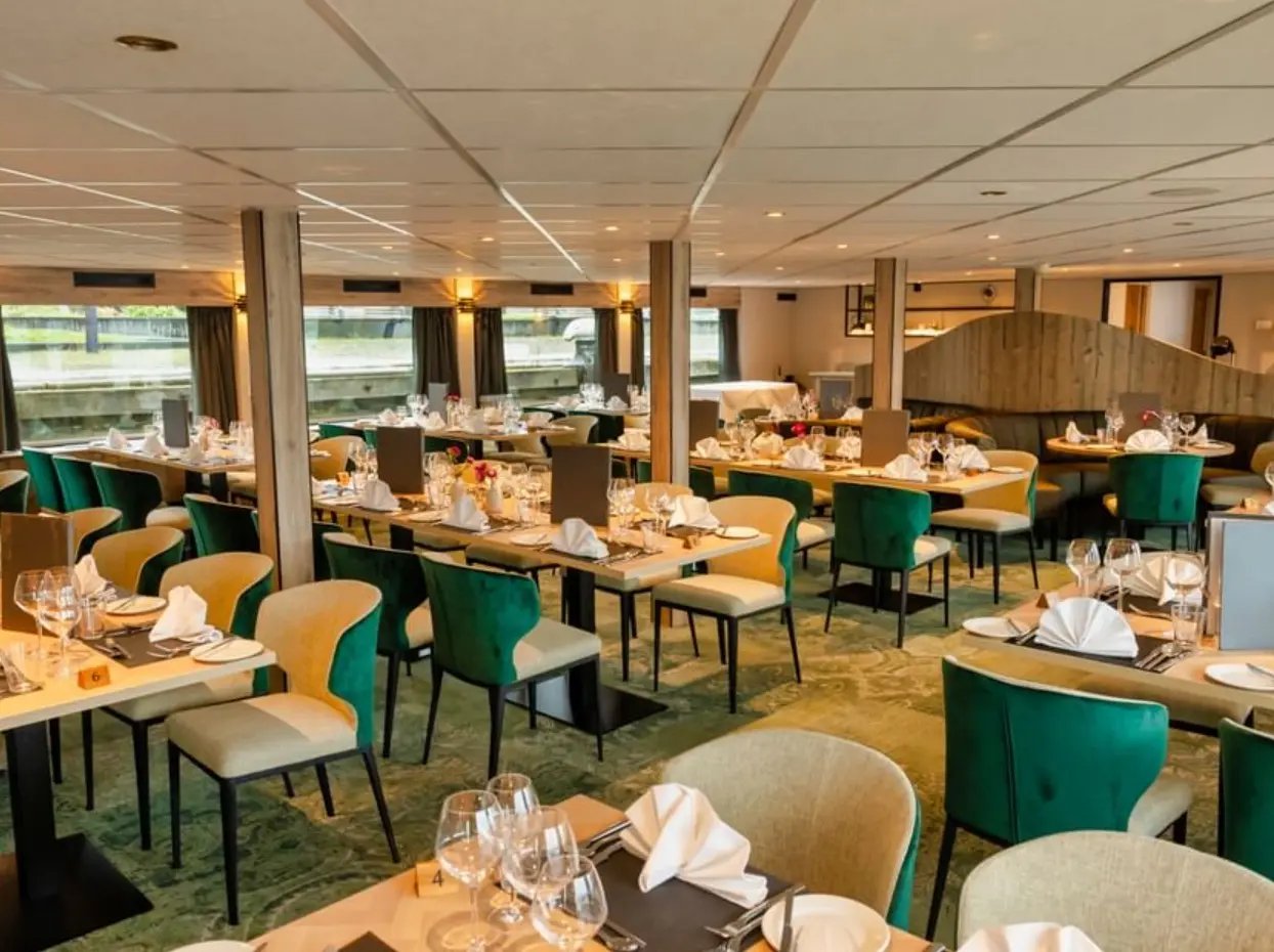 Grosszügiges Bordrestaurant mit mehreren Tischreihen, gedeckten Plätzen, Polsterstühlen und Fensterfront