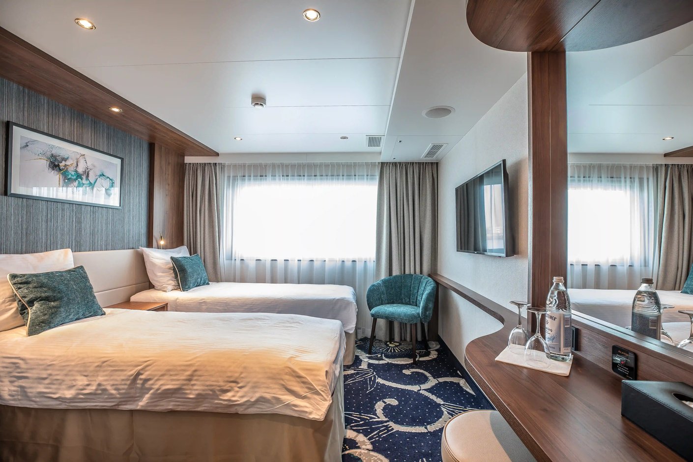 Helle Schiffskabine mit zwei Einzelbetten, Sessel, Spiegelwand und grossem Fenster