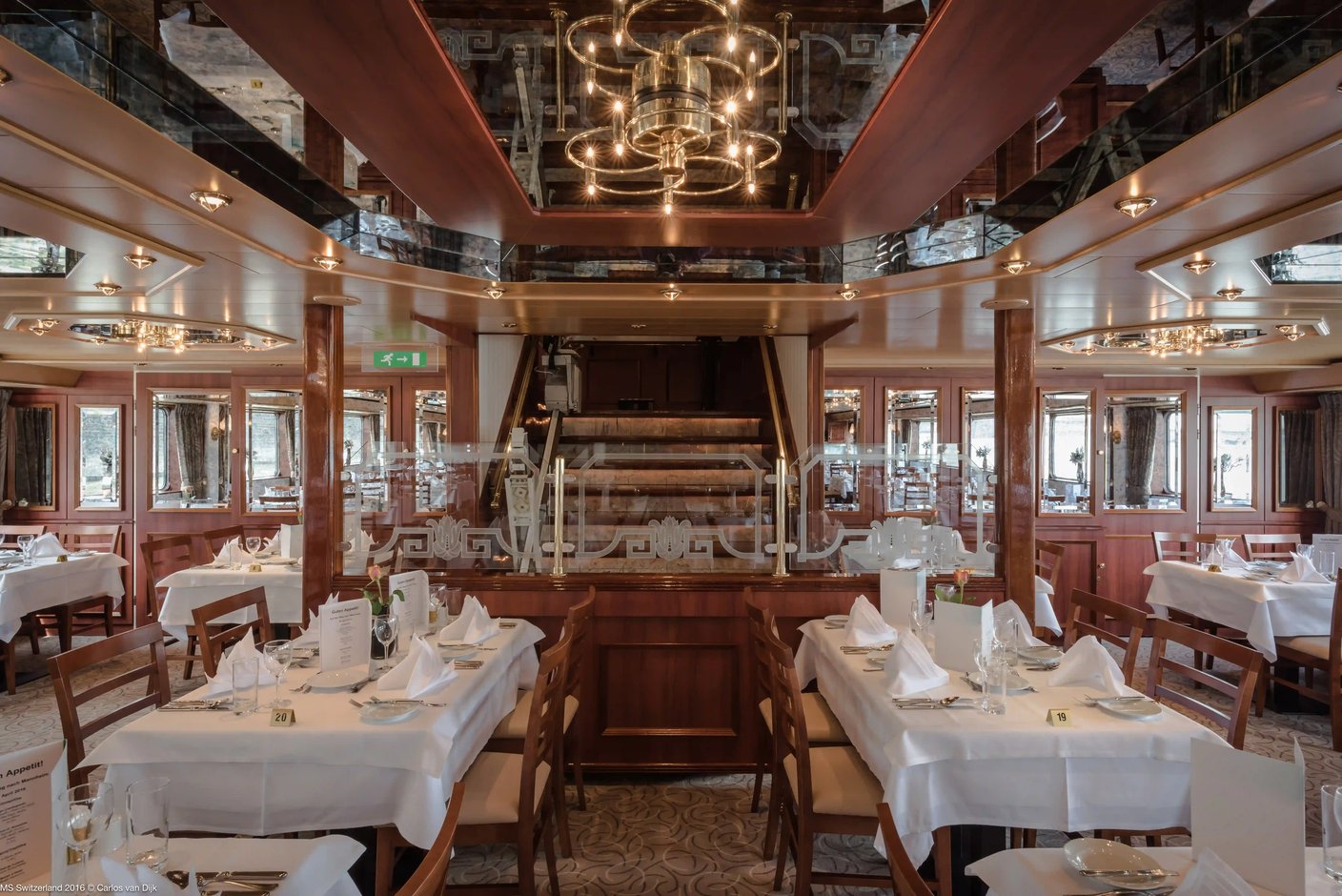 Blick in das stilvolle Schiffsrestaurant mit weiss gedeckten Tischen, Holzstühlen und grossen Fenstern mit Blick nach draussen.
