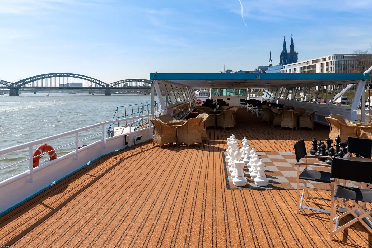Blick über das Sonnendeck der MS Switzerland mit einem grossen Bodenschachspiel, Sitzgruppen und einem überdachten Bereich vor der Kulisse des Kölner Doms.