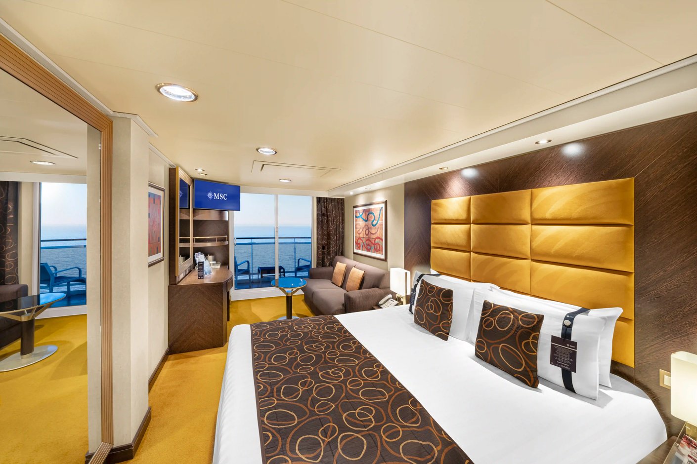 Hochwertige Balkonkabine Aurea auf der MSC Fantasia mit Doppelbett, Sitzecke und privatem Balkon mit Meerblick.