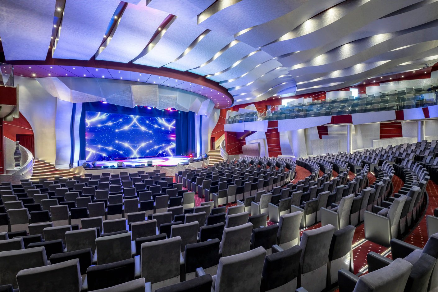 Grosses Theater der MSC Fantasia mit geschwungener Decke, moderner Bühne, Beleuchtungseffekten und zahlreichen Sitzreihen.