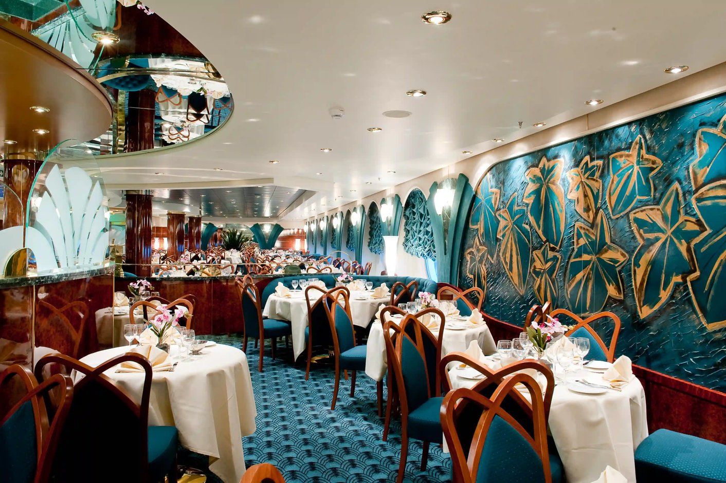 Elegantes Restaurant auf der MSC Magnifica mit gedeckten Tischen, gepolsterten Stuehlen und dekorativen Wandmotiven.