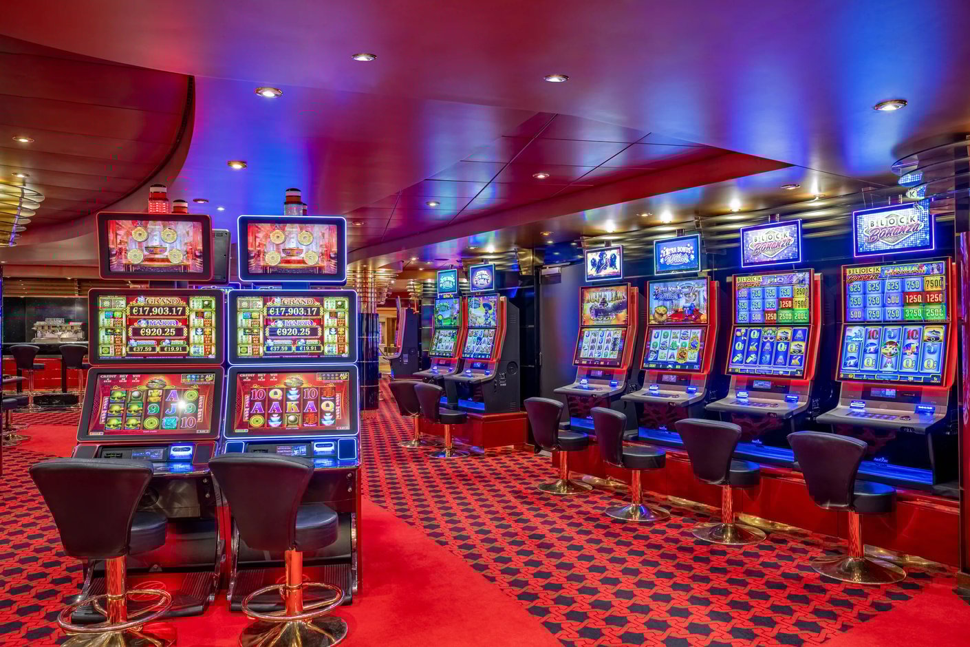 Casino auf der MSC Poesia mit Spielautomaten, Sitzhockern, rotem Teppich und farbiger Beleuchtung