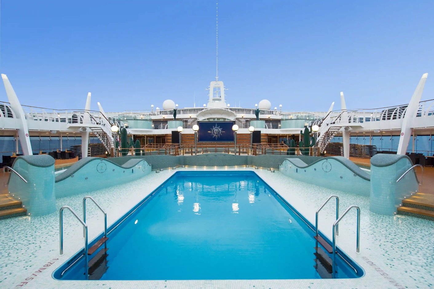 Aussenpool auf dem Deck der MSC Preziosa mit blauem Wasser, Treppen und Sitzbereichen