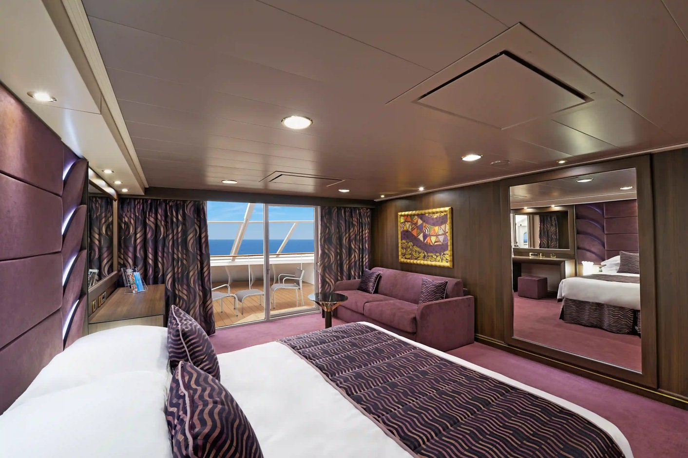Deutsch: Elegante Yacht Club Suite der MSC Preziosa mit Doppelbett, Sitzecke, Balkon und Meerblick