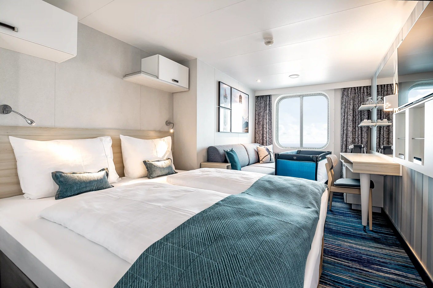 Helle Aussenkabine mit Doppelbett, Sofa, Schreibtisch und Fenster mit Meerblick