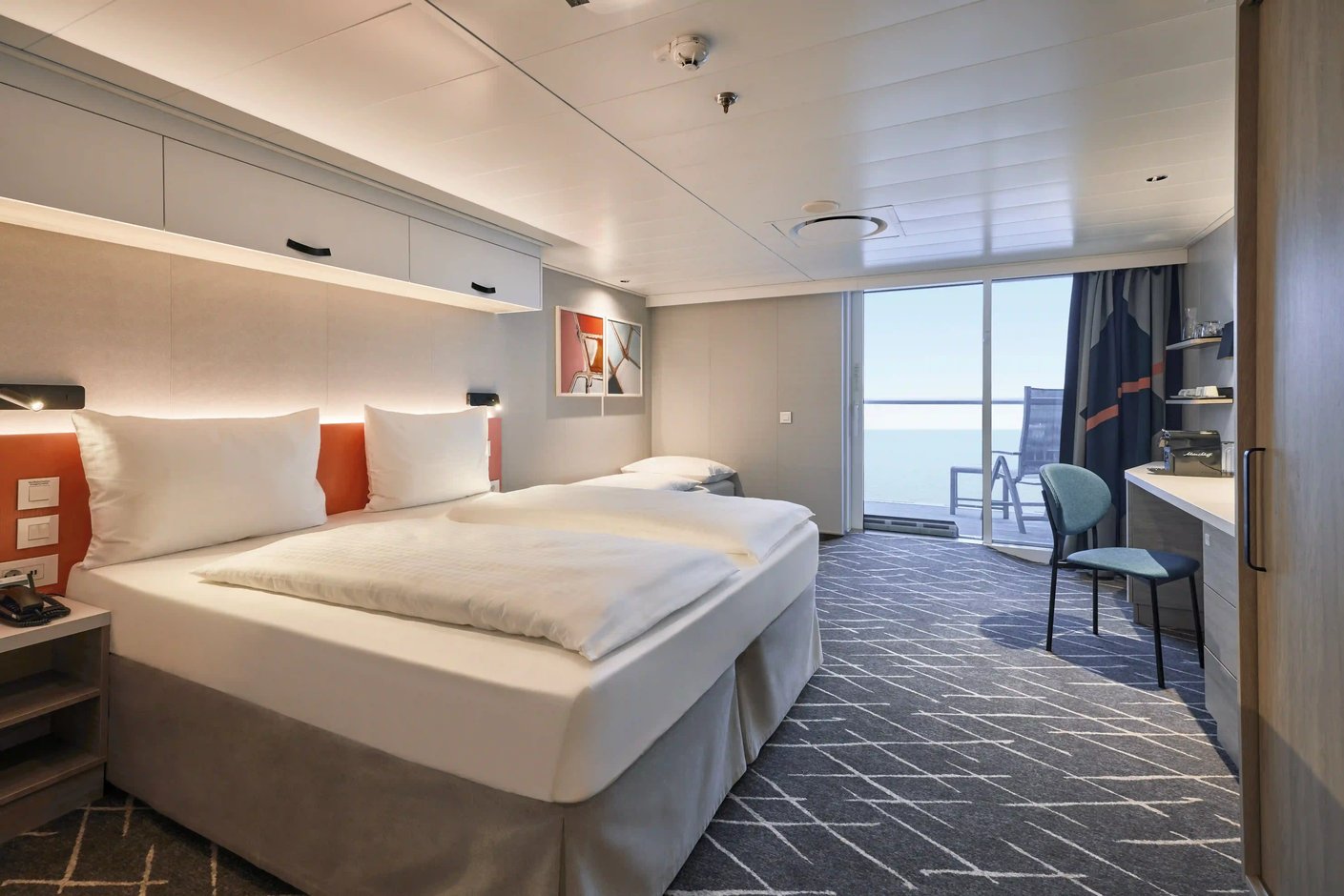 Balkonkabine mit Doppelbett, Sitzbereich und Zugang zum Balkon mit Meerblick