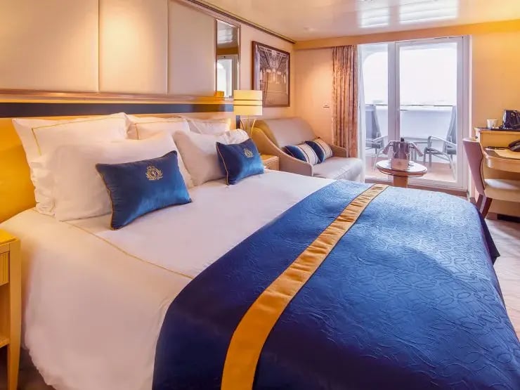 Balkonkabine mit Doppelbett, Sofa und Balkon mit Sitzmöbeln