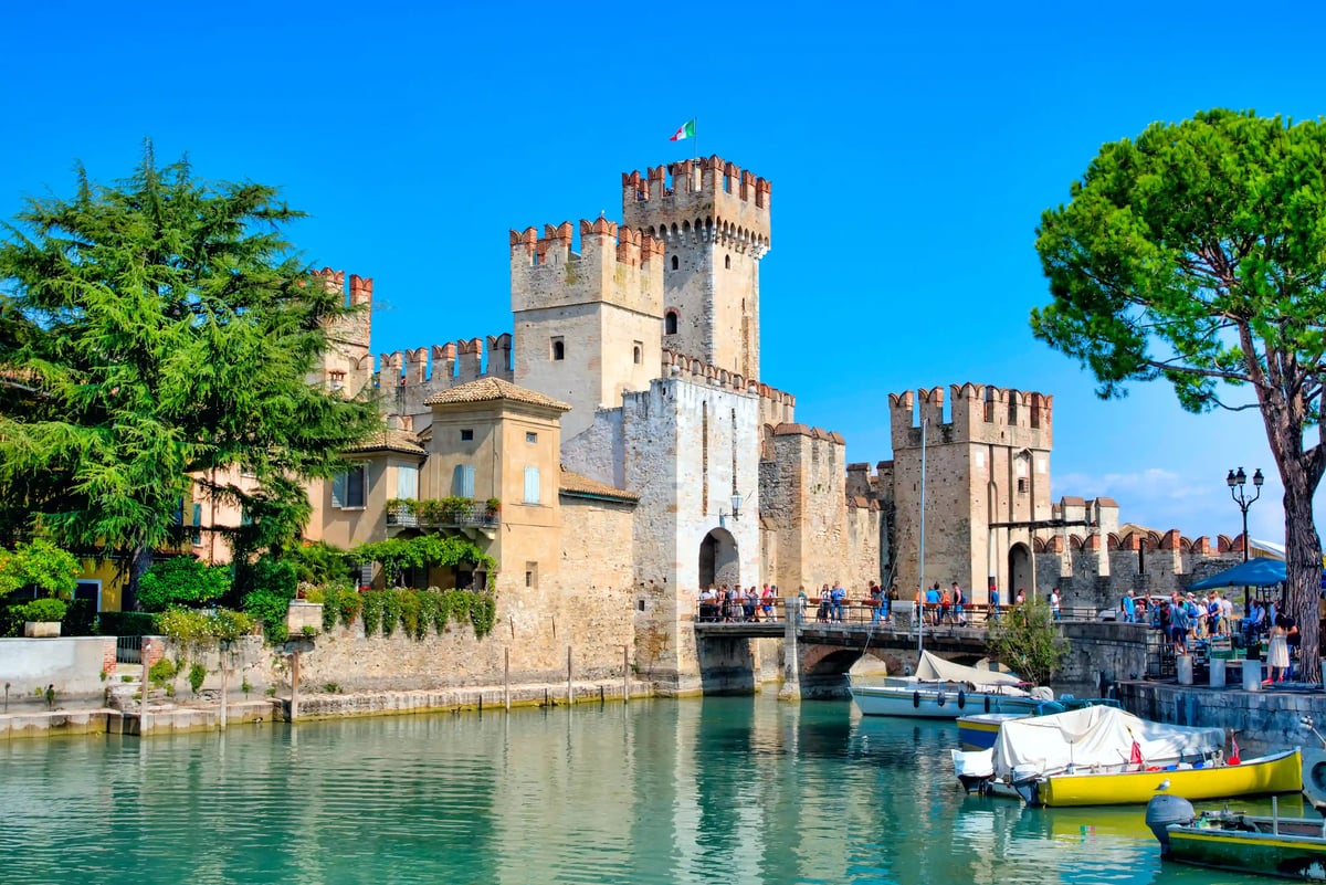 Chateau médiéval de Sirmione avec tours pont et bateaux au bord du lac de Garde